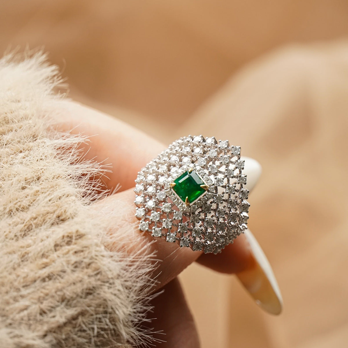Personalized French-inspired ring with diamond inlay and green gemstone, displayed on a hand wearing a soft sweater.